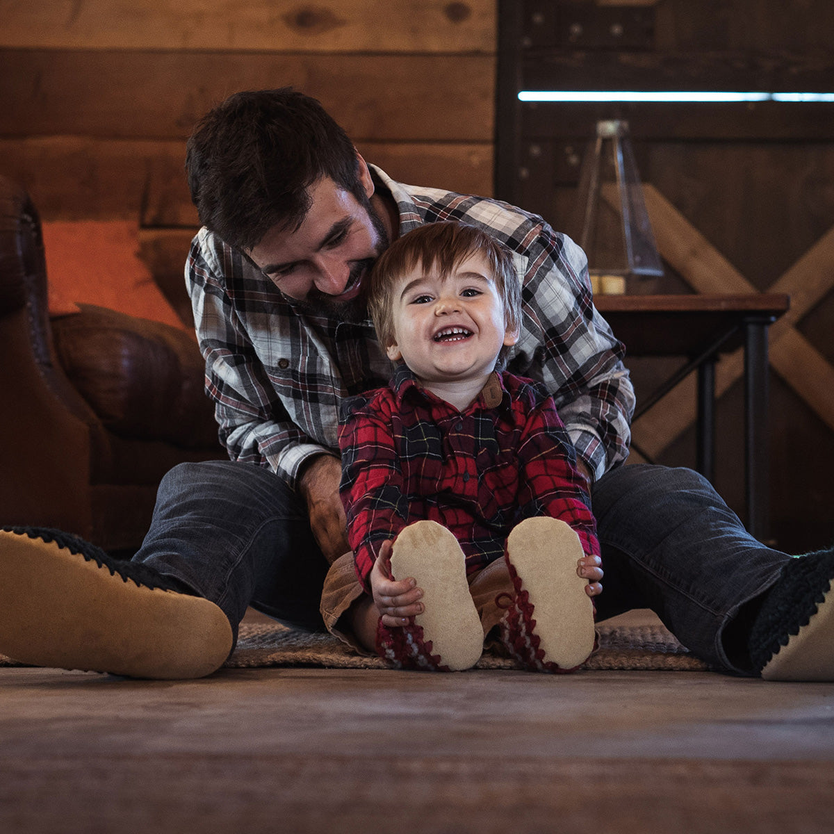 Father and son sitting on floor wearing their Padraig Slippers