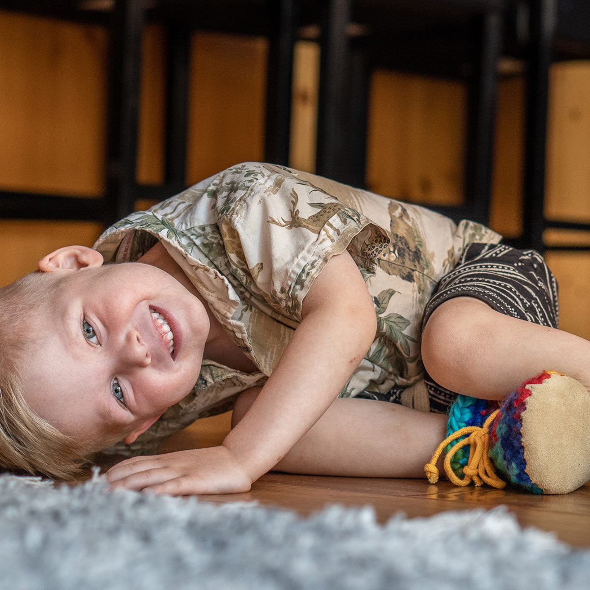 Boy wearing his Padraig Slippers lying on the floor